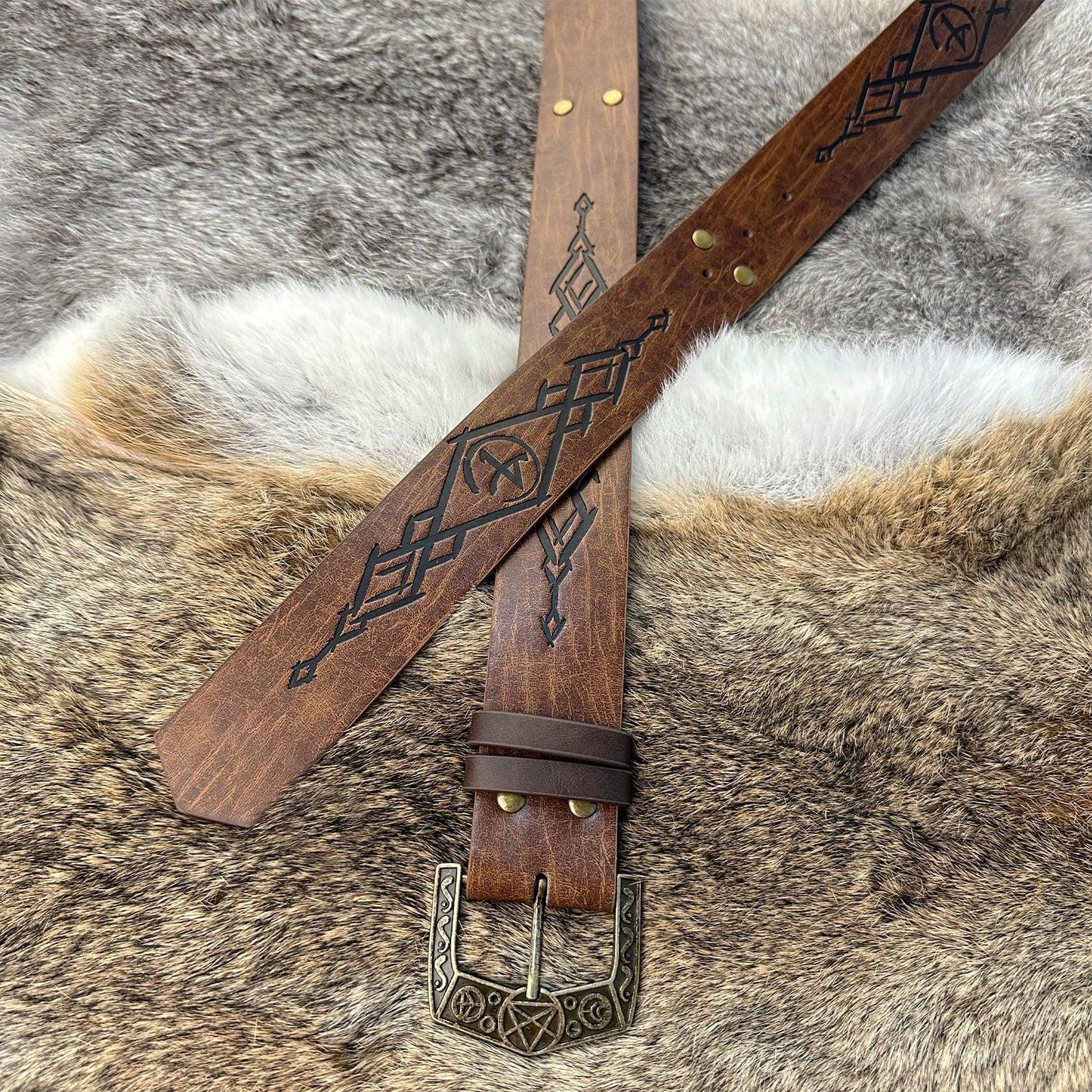 Medieval style brown leather belt with engraved patterns and ornate metal buckle on fur background
